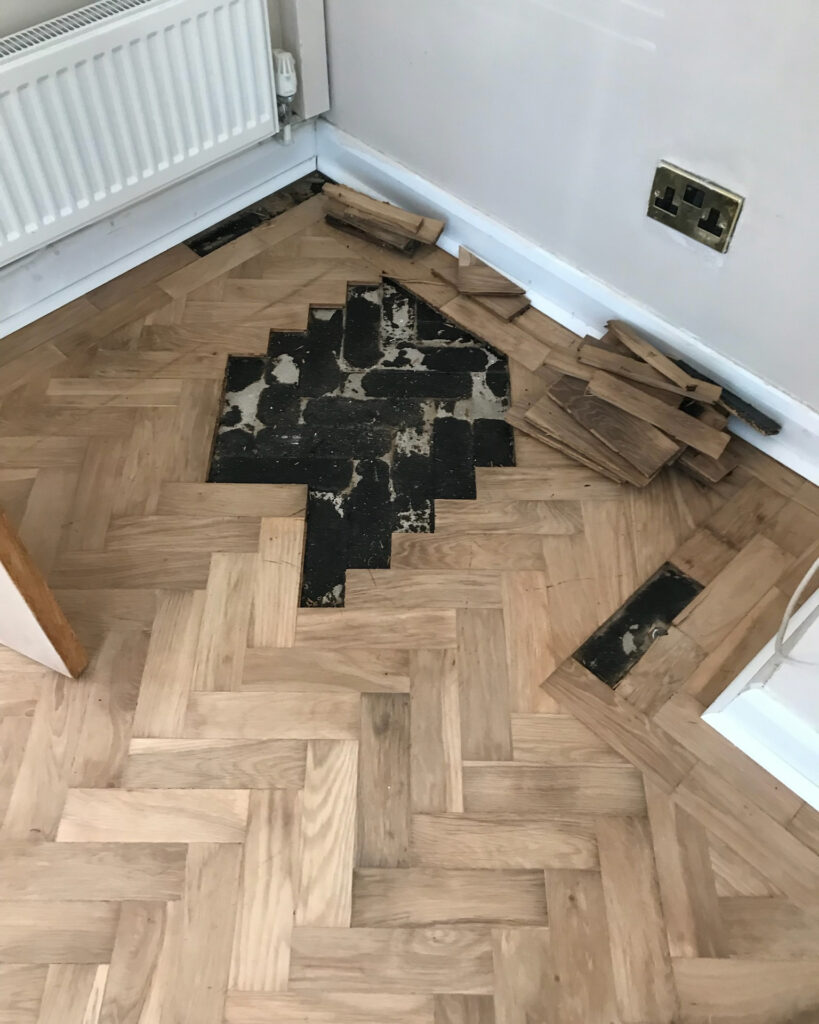 Image shows parquet wood flooring being repaired and restored by Mark Antony & Sons in Kent. Parquet blocks have been removed to be restored and re-adhered to the subfloor.