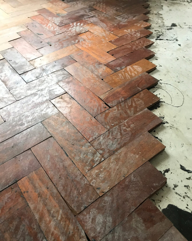 Image showing a damaged parquet wood floor being restored and repaired by Mark Antony & Sons in Kent.